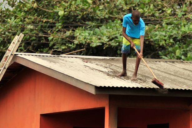 A local resident clears ash from a roof after a series of eruptions