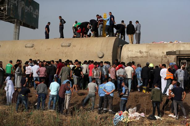 People inspect the damage at the site where train carriages derailed in Qalioubia province