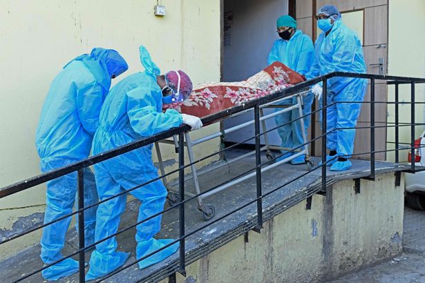 Members of medical staff wearing protective gear carry the dead body of a Covid-19 coronavirus victim at a hospital in Amritsar