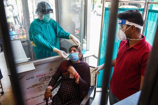 A health worker collects a nasal swab sample from a woman to test for Covid-19