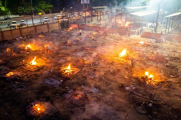 Men are seen around the burning pyres of victims