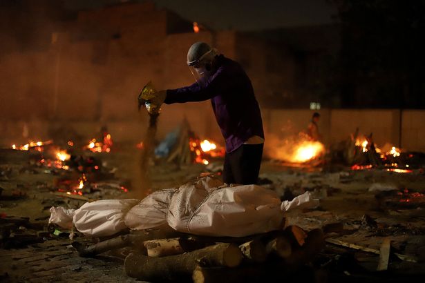 A man performs last funeral rites for a coronavirus victim at a cremation ground in New Delhi