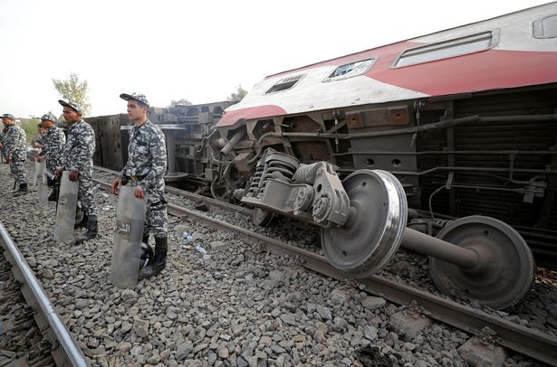 Egyptian police officers stand guard at the site where train carriages derailed in Qalioubia province, north of Cairo, Egypt