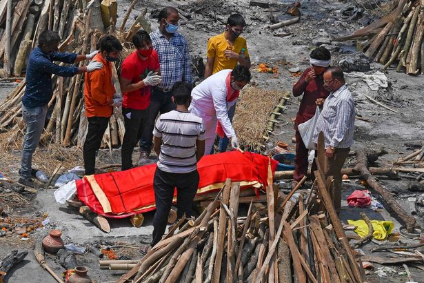 Family members and relatives perform the last rites amid the funeral pyres of victims who died of the Covid-19 coronavirus during mass cremation held at a crematorium in New Delhi