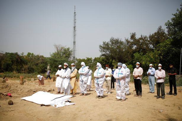 Muslim men offer funeral prayers for a man who died from the coronavirus disease (COVID-19), during his funeral at a graveyard in New Delhi, India