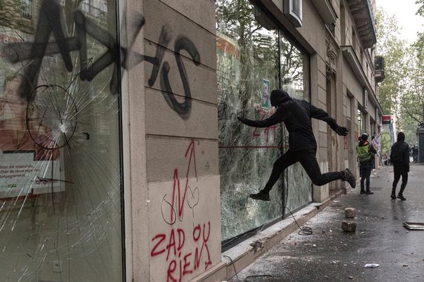 A protester kicks in a bank window at the International Labour Day protests in Paris