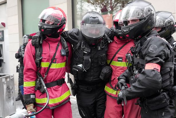 Firefighters carry a police officer away from clashes at the traditional May Day protests in Paris