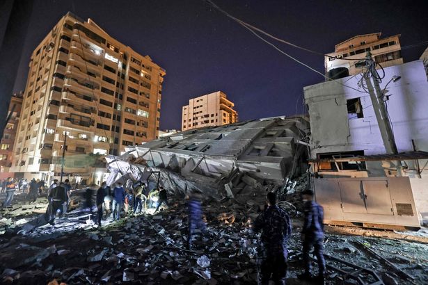 People gather at the site of a collapsed building in the aftermath of Israeli air strikes