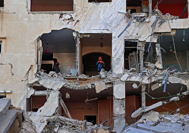 Palestinian women check the damage inside an apartment in a heavily-damaged building in Gaza City