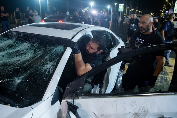 An Israeli police officer inspects the car