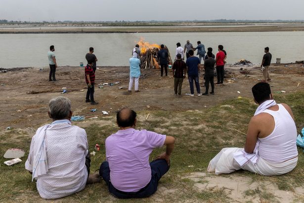 Relatives watch during the cremation of a man