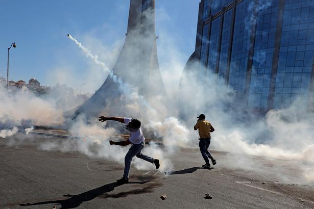 Palestinian demonstrators throw teargas canisters back at Israeli forces