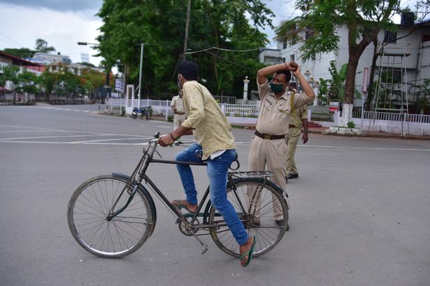 A police officer wields his baton against a man as a punishment for defied curfew due to rise of COVID-19 coronavirus cases in Nagaon District of Assam ,India