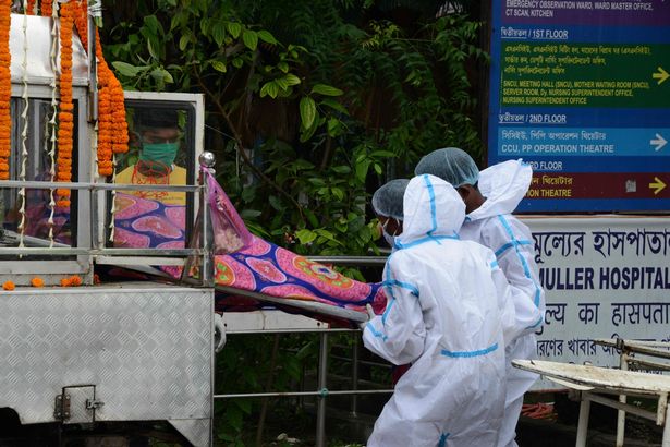 Hospital workers wearing PPE kit carry the dead body of a Covid patient who died at Siliguri district hospital