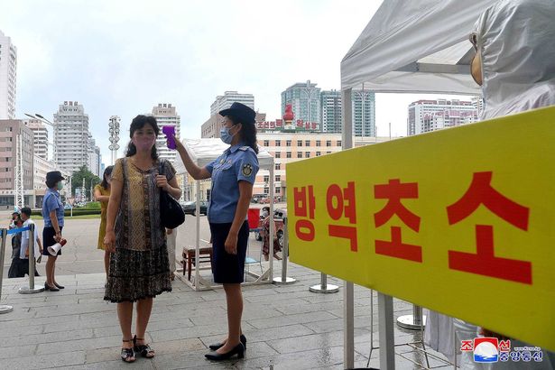 undated picture released from North Korea's official Korean Central News Agency (KCNA) on August 29, 2020 shows a station employee checking the body temperature of a passenger as a measure to prevent the spread of the COVID-19 coronavirus in Pyongyang