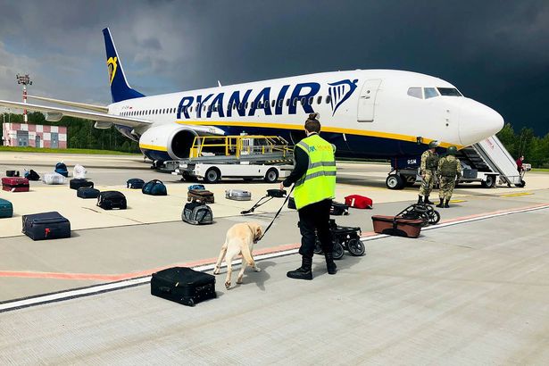 A Belarusian dog handler checks luggage off the Ryanair Boeing 737-8AS