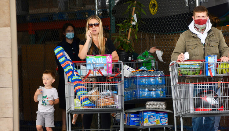 woman and child at grocery store not wearing masks with man wearing mask
