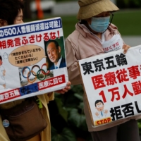 Protesters opposed to Japan going ahead with hosting the Olympics this summer hold banners denouncing requests by the government for the dispatch of doctors and nurses to help out with the games, during a protest in Tokyo last week. | REUTERS