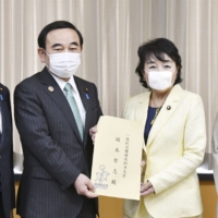 Kuniko Inoguchi, a Liberal Democratic Party lawmaker, submits a proposal to promote the four-day workweek to Tetsushi Sakamoto, minister for promoting dynamic engagement of all citizens, in April in Tokyo. | KYODO 
