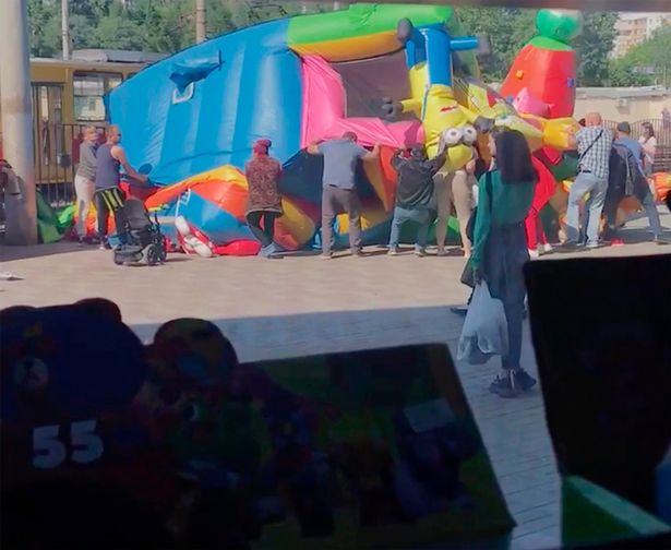 People cut and wrap a bouncy castle that exploded in Russia