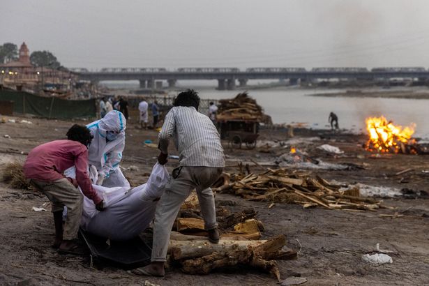 People place the body of a man who died from the coronavirus disease (COVID-19), on a pyre