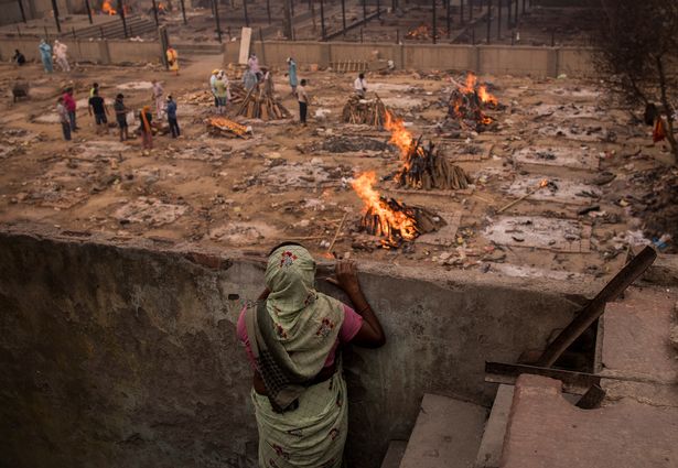 A lady looks at the burning funeral pyres