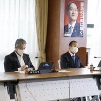 Tsutomu Sato (left) and other lawmakers attend a meeting of the Liberal Democratic Party's General Council at the party's headquarters in Tokyo on Friday.