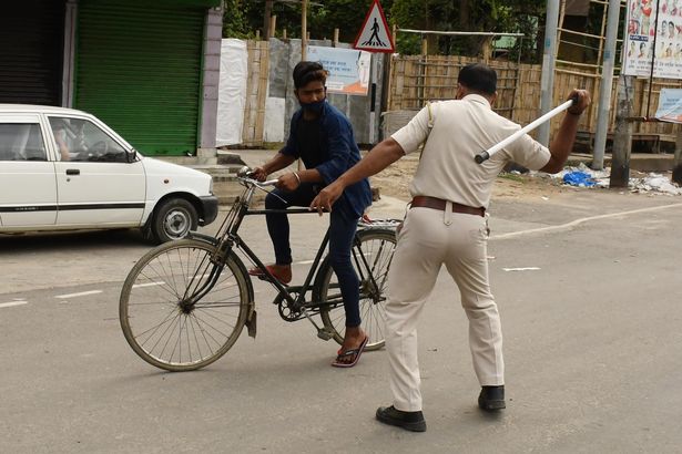 A police officer wields his baton against a man as a punishment for defied curfew due to rise of COVID-19 coronavirus cases in Nagaon District of Assam ,India