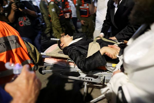 Rescue workers transport an injured boy to an ambulance outside a synagogue