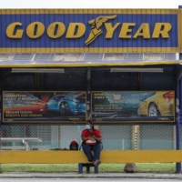 A woman sits at a bus stop outside Goodyear factory in Shah Alam, Malaysia, on May 6. | REUTERS