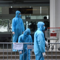 Medical workers stand outside a quarantined building in Hanoi earlier this year.  | REUTERS