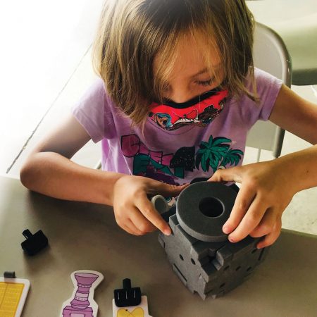 a kid wearing a purple shirt working on a science project