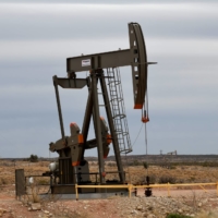 A pump jack operates in front of a drilling rig owned by Exxon near Carlsbad, New Mexico, in February 2019.  | REUTERS