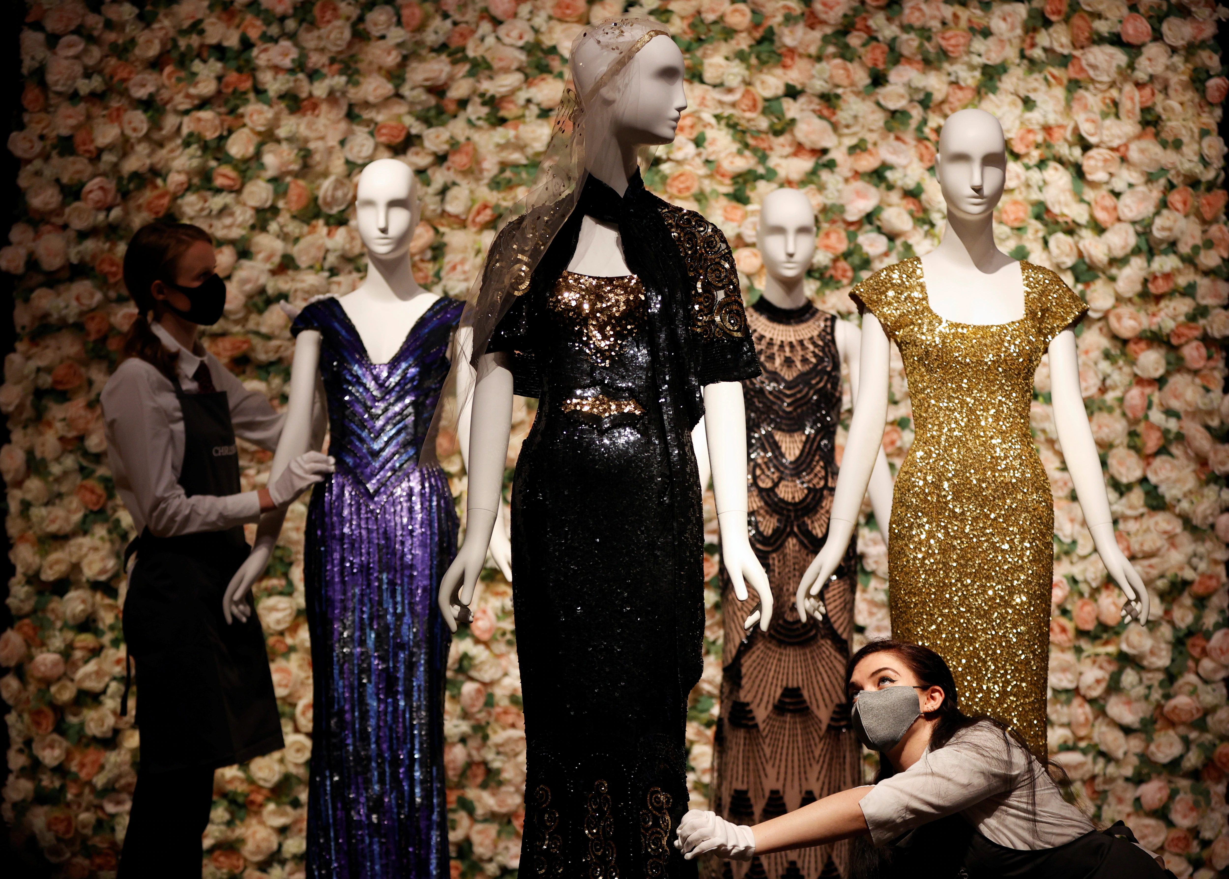 Gallery assistants pose for a photograph next to a black and gold ‘Oscar’ dress worn by Nicole Kidman by designer L’Wren Scott at Christie’s in London, Britain, June 10, 2021. (REUTERS)