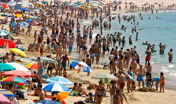 Tourists sunbathe and swim at the beach near the apartment where Madeleine went missing