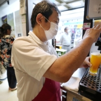 A manager serves alcohol at an izakaya pub in Tokyo on Monday evening. | KYODO