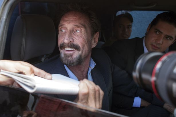 John McAfee is met by cameras at an airport in Guatemala