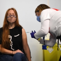 A woman receives a dose of Pfizer's COVID-19 vaccine inside a temporary vaccination center set up a the Emirates Stadium in London on Friday. | AFP-JIJI