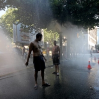 Residents walk through a temporary misting station as temperatures rise in Vancouver on Monday. | BLOOMBERG