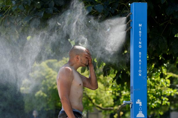 A man cools off at a misting station during the scorching weather