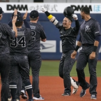 Takahiro Okada lifts his arms in celebration after hitting a sayonara single against the Carp in Osaka on Sunday. | KYODO