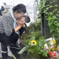 A woman prays Tuesday at the scene of a traffic accident in Yachimata, Chiba Prefecture, the day before, in which two schoolchildren were killed and three others were injured. | KYODO