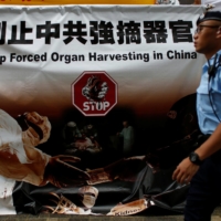 A policeman walks past a protest banner by Falun Gong outside the International Congress of Transplantation Society in Hong Kong in August 2016. U.N. rights experts said Monday they had 'credible information' that detainees from minority communities in China may be being subjected to forced organ harvesting, a claim fiercely rejected by Beijing. | REUTERS