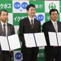 Chiba's then-Mayor Toshihito Kumagai (center) makes a declaration in November 2015 at Chiba City Hall with others among government, industry and academia to foster management that will promote paternity child care leave. | KYODO