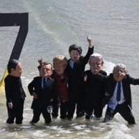 Extinction Rebellion environmental activists with masks of G7 leaders protest on the beach in St Ives, Cornwall, during the G7 summit on Sunday. | AFP-JIJI