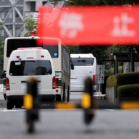 Buses believed to be carrying American Michael Taylor and his son Peter, extradited to Japan in March and accused of helping former Nissan Motor Co. Chairman Carlos Ghosn flee Japan, arrive at the Tokyo district court on June 14. | REUTERS