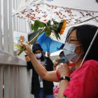 A supporter gives a flower and card to employees of Apple Daily at Next Digital’s headquarters in Hong Kong on Wednesday.  | REUTERS