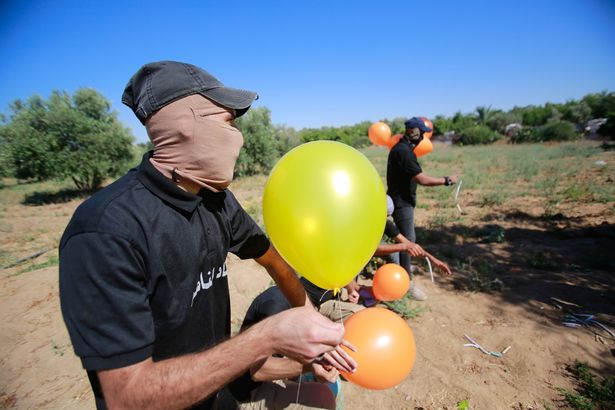 Masked Palestinians launch incendiary balloons from the Gaza Strip towards Israel