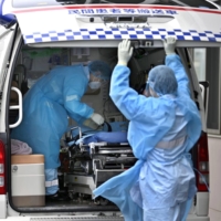 Emergency medical staff leave a hospital after transporting a COVID-19 patient in Sakai, Osaka Prefecture, last month. | KYODO