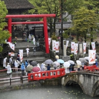 An Olympic torch relay runner arrives at Aoiaso shrine in Hitoyoshi, Kumamoto Prefecture, on May 5. Along with Gunma and Ishikawa prefectures, Kumamoto Prefecture will be taken out of a quasi-state of emergency after the coming weekend. | KYODO